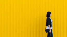 A female walks in front of a yellow clad structure - header image from the graphic design blog by nstudio