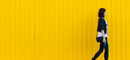 A female walks in front of a yellow clad structure - header image from the graphic design blog by nstudio
