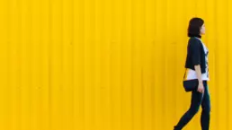 A female walks in front of a yellow clad structure - header image from the graphic design blog by nstudio