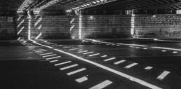 a black and white photograph of an underpass, light breaks through and forms lines across the scene