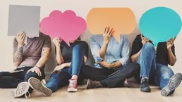 a group of four seated creatives hold up colourful paper cut outs of speech bubbles, covering their faces - header image from the graphic design blog by nstudio