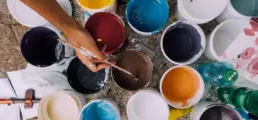 A man dipping a paintbrush into a paint container, taking brown paint - header image from the graphic design blog by nstudio