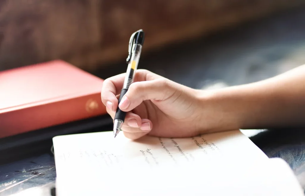 a female hand holds a pen above a notebook