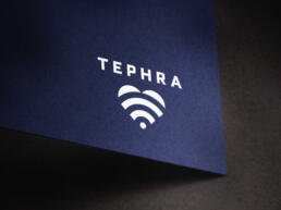 Mockup of the TEPHRA logo in white on blue textured board