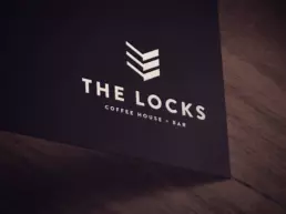 the locks cafe logo design mocked up on a dark board
