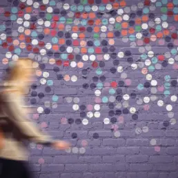 decay 3 circular artwork mocked up onto a mural setting. A blurred pedestrian walks across the shot.