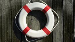 a white water rescue ring with four red stripes and white rope
