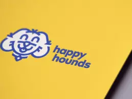 the happy hounds logo printed onto yellow board
