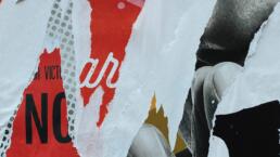 a close up photo of a poster site, where multiple posters have been torn, revealing the others