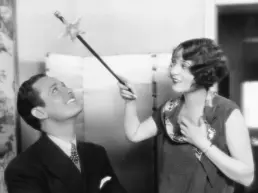 vintage photograph of a woman holding a magic wand over a man's head