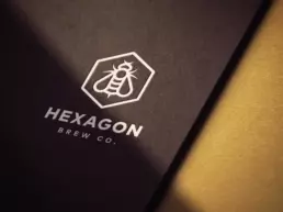 hexagon brew co logo mockup debossed in white onto dark brown paper board