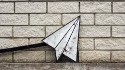 A street sign of a paper aeroplane