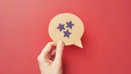 a hand holds a cut out of a speech bubble with a stars drawn on it
