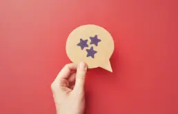 a hand holds a cut out of a speech bubble with a stars drawn on it