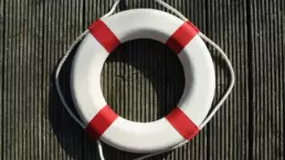 a white water rescue ring with four red stripes and white rope