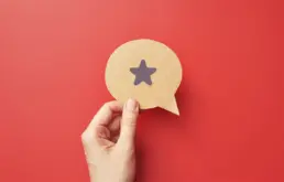 a hand holds a cut out of a speech bubble with a bookmark icon drawn on it