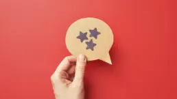 a hand holds a cut out of a speech bubble with a stars drawn on it