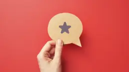 a hand holds a cut out of a speech bubble with a star icon drawn on it