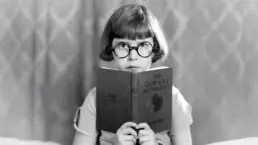 a vintage photograph of a young girl studying a mathematics book