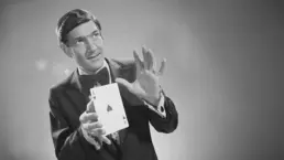 a vintage image of a magician holding an oversized ace of hearts playing card