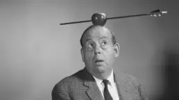 a vintage portrait of a man with an apple on his head. an arrow has pierced the apple, to his surprise