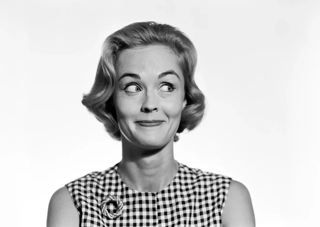 a mid 20th century lady in black and white, she is looking to the right side of the frame